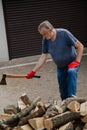 Elderly man with ax stands in front of pile of firewood Royalty Free Stock Photo