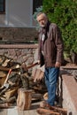 Elderly man in jacket stands in front of pile firewood Royalty Free Stock Photo