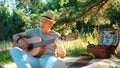 A man with a beard plays the guitar, relaxing in nature on a summer evening in the rays of the setting sun. Royalty Free Stock Photo