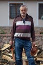 Elderly man with ax stands in front of pile of firewood Royalty Free Stock Photo