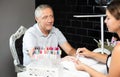 Elderly man in beauty salon - manicurist gives shape to man nails