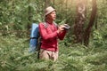 Elderly man birdwatching while standing outdoors in forest, scanning his surroundings with binoculars, male dressed casual red Royalty Free Stock Photo