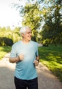 An elderly man in a blue T-shirt is jogging through a summer park. Royalty Free Stock Photo