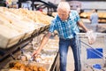 Elderly man buying bread and pastries in grocery section of the supermarket Royalty Free Stock Photo