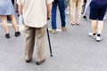 Elderly man with a cane on the background of young people. The concept of youth and old age