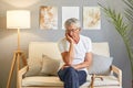 Elderly man with a cane. Grandfather's old on couch. unhappy man pensioner wearing white T-shirt and jeans sitting on sofa Royalty Free Stock Photo