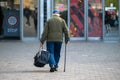 Elderly man with cane walking down the street, rear view, concept for disability, old age, limping