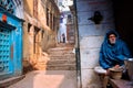 Elderly man in a cape sitting alone on the street of the ancient indian city