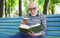 Elderly man in casual reading outdoors