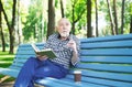 Elderly man in casual reading outdoors