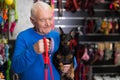 Elderly man chooses and buys leash for his doberman pinscher dog at pet shop