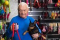 Elderly man chooses and buys leash for his doberman pinscher dog at pet shop