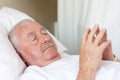 Elderly man with closed eyes lying in hospital bed Royalty Free Stock Photo