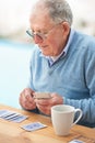 Elderly man, coffee and playing cards on table for poker, relax and happy in retirement. Senior person, grandfather and Royalty Free Stock Photo