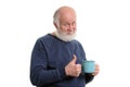 Elderly man with cup of bad tea or coffee showing thumb up isolated on white