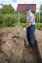 An elderly man is digging the earth to build a deep bed of Royalty Free Stock Photo