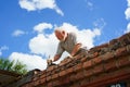 an elderly man dismantles the old brickwork and lays new bricks on the roof.