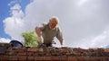 An elderly man dismantles the old brickwork and lays new bricks on the roof.