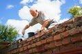 an elderly man dismantles the old brickwork and lays new bricks on the roof. Royalty Free Stock Photo