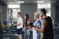 Elderly man doing exercise with group of younger people at gym. Royalty Free Stock Photo