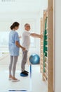 Man doing gymnastic exercises with a young female physiotherapist Royalty Free Stock Photo