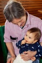 Elderly Man with Downs Syndrome Holding Baby and Looking at Her