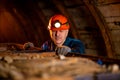 An elderly man dressed in work overalls and a helmet stands near the old inverted vogonetki. Miner Royalty Free Stock Photo