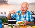 elderly man eating fresh vegetable salad at home