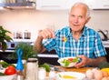 Elderly man eating fresh vegetable salad at home Royalty Free Stock Photo