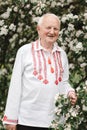 Elderly man in embroidered ethnic shirt in nature. Ukrainian traditional clothes