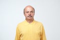 Elderly man emotions, portrait of serious senior caucasian man looking at camera against gray wall