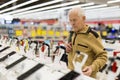 Elderly man examines smart watch in showroom of electronics store