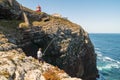 Elderly man fishing with a rod on high cliffs of Sao Vicente Cape, Portugal