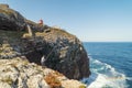 Elderly man fishing with a rod on high cliffs of Sao Vicente Cape, Portugal