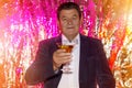 An elderly man with a glass of martini makes a celebratory toast against a shiny red background Royalty Free Stock Photo