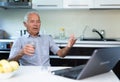 Elderly man with glass of wine communicates virtually using a laptop and the Internet
