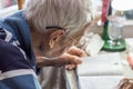 Elderly man with glasses reading writings in notebook near the window at home Royalty Free Stock Photo