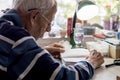 Elderly man with glasses reading writings in notebook near the window at home Royalty Free Stock Photo