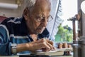 Elderly man with glasses reading writings in notebook near the window at home Royalty Free Stock Photo