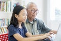 Elderly man and granddaughter use laptop on table Royalty Free Stock Photo