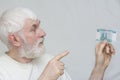 an elderly man with a gray beard gleefully holds a bill of 1000 rubles