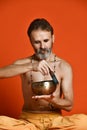 Elderly man with a gray beard yogi in good physical shape holding singing bowl