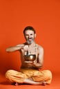 Elderly man with a gray beard yogi in good physical shape holding singing bowl
