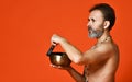 An elderly man with a gray beard yogi in good physical shape holds a singing bowl for yoga