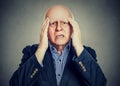 Elderly man with hands on his temples has a headache