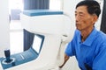 Elderly man having hes eyes examined by an eye doctor on a testing tool in modern clinic Royalty Free Stock Photo