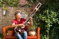 Elderly man in his garden is playing a sitar Royalty Free Stock Photo