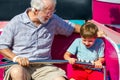 An Elderly Man and His Young Grandson Ride on a Spinning Carnival Ride the Man is Looking at the Little Boy Royalty Free Stock Photo