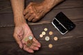 An elderly man holding an old coin purse and coins . The concept of poverty in retirement Royalty Free Stock Photo