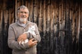 An elderly man holds a cute white kitten